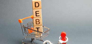 U.S. Economy Could Get Ugly: Consumer Debt Surges Past $17 Trillionn a supermarket trolley and a human figurine bound by handcuffs. Mandatory payment of debt. Alimony payment. Pay of a mortgage loan. Debt load / obligation. IOU